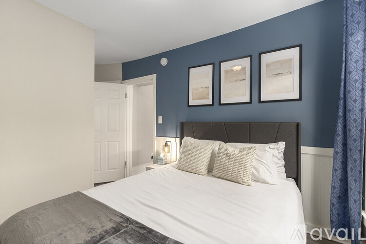 A bedroom with a bed, pillows, and pictures on the wall.