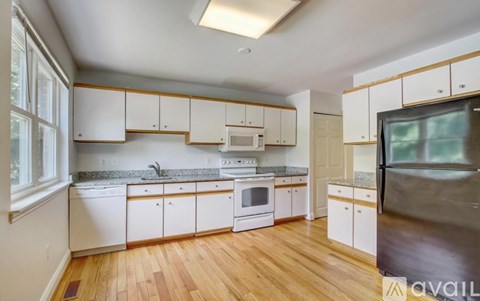 A kitchen with white cabinets and a wooden floor.