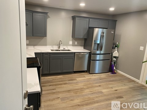 A kitchen with a stainless steel refrigerator and wooden flooring.