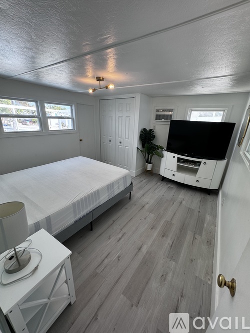 A bedroom with a bed, a television, and a window.