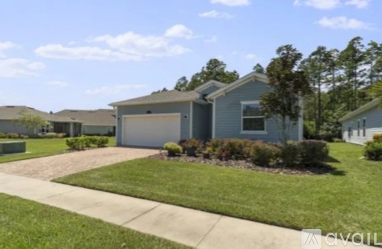 A house with a grey roof and a white garage door is surrounded by a well-kept lawn.