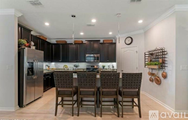 A kitchen with a table and chairs in front of a refrigerator.
