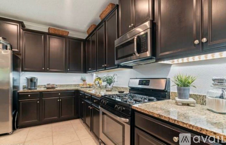 A kitchen with dark brown cabinets and a granite countertop.