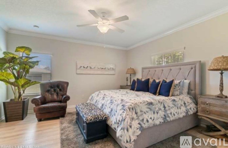 A bedroom with a large bed, a chair, and a plant.