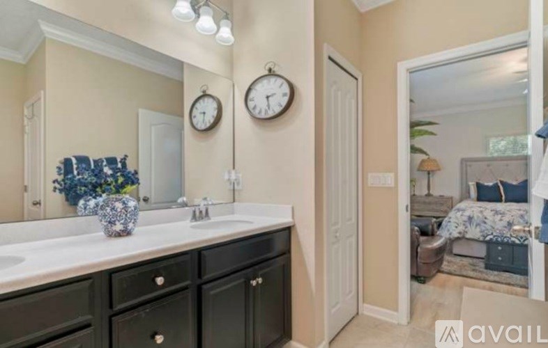 A bathroom with a vanity, two clocks, and a mirror.