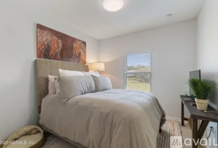 A bedroom with a bed, nightstand, and a painting on the wall.