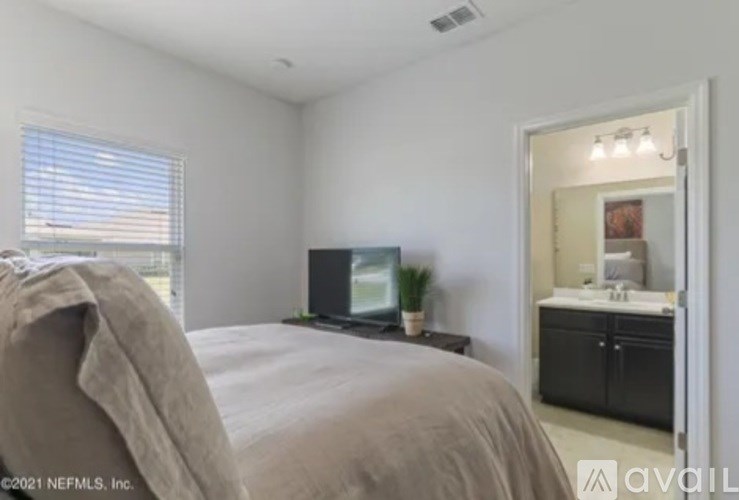 A bedroom with a bed, a television, and a bathroom visible through the door.