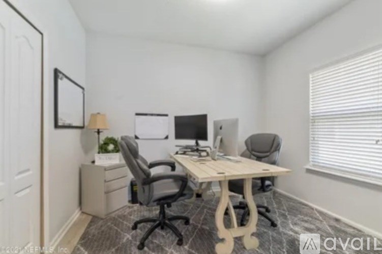 A room with a desk, chairs, and a computer.