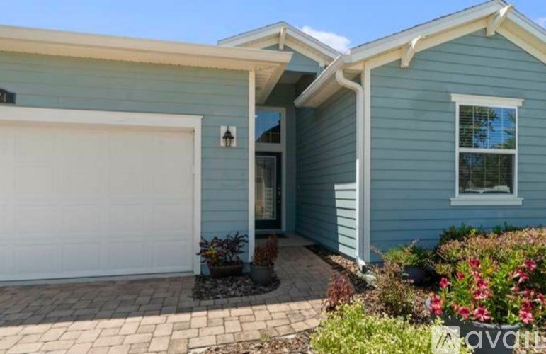 A blue house with a white garage door and a brick walkway.