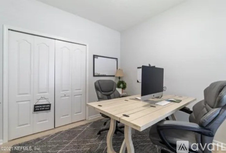 A room with a desk, chair, and a television.