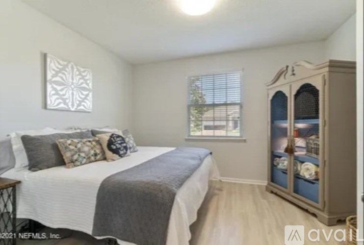 A bedroom with a bed, pillows, a window, and a cabinet.