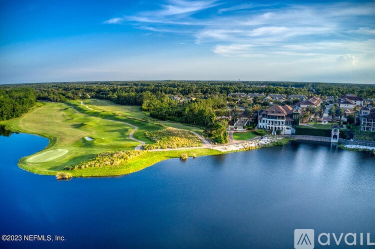 A golf course with a lake and houses in the background.