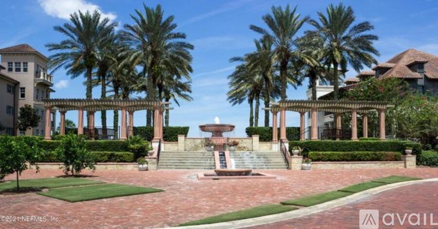 A large house with a fountain in the middle of a garden.