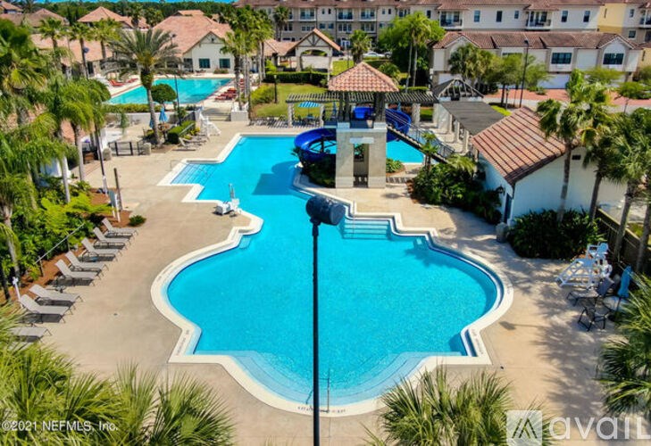A large swimming pool surrounded by palm trees and lounge chairs.