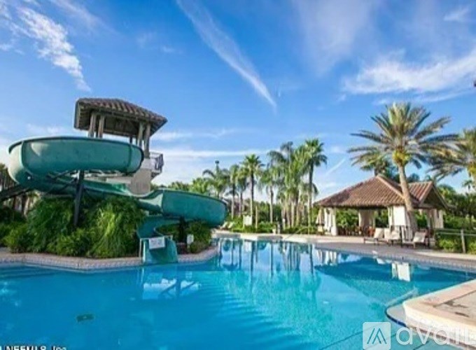 A large swimming pool with a slide and a pavilion in the background.