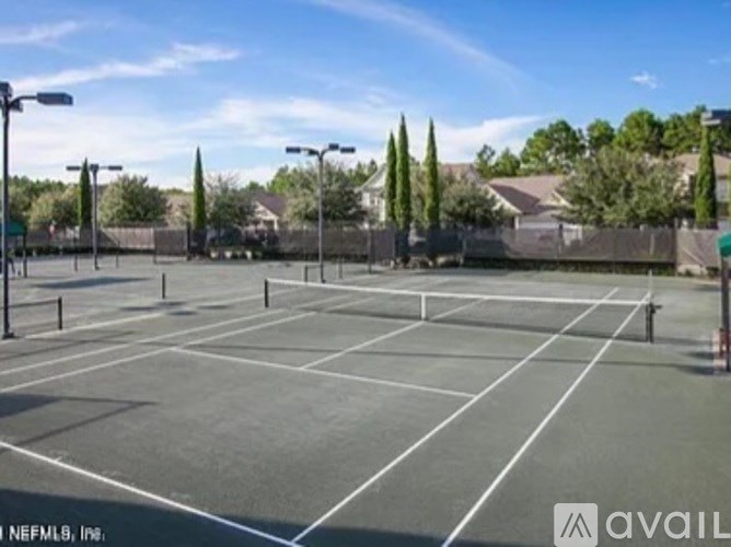 A tennis court with a net and trees in the background.