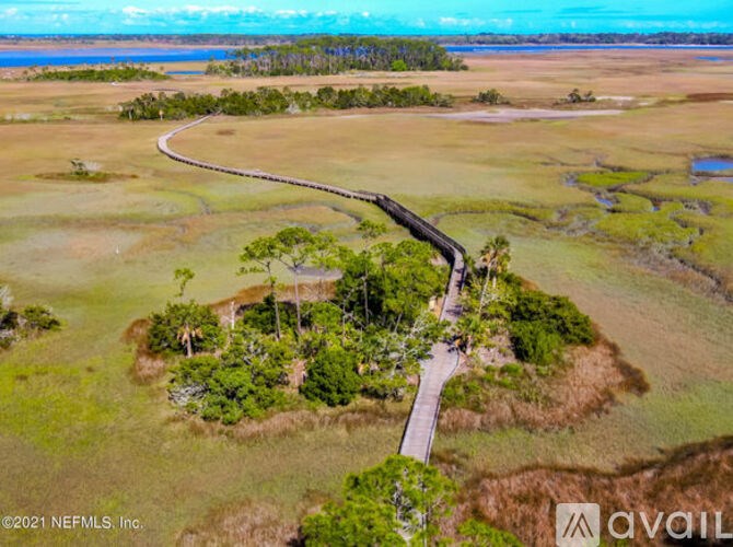 A winding road through a green landscape with a body of water in the distance.