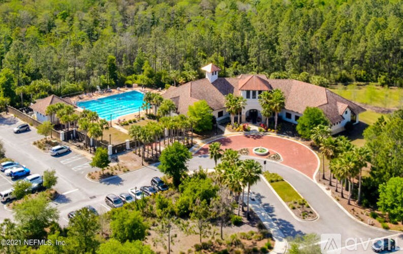 A bird's eye view of a residential area with a swimming pool and a roundabout.