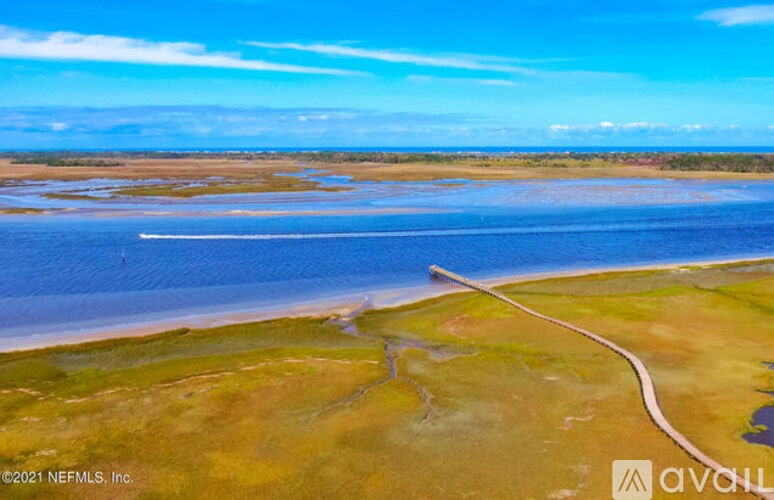 A winding road cuts through a grassy landscape towards a body of water.