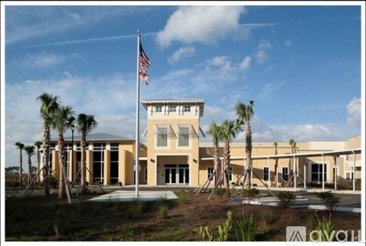 A building with a flag on top and palm trees in front.