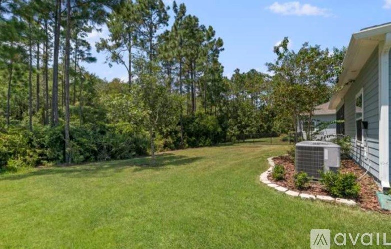 A house with a green lawn and trees in the background.
