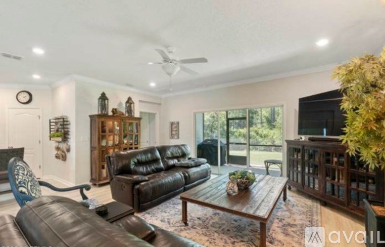A living room with a black leather couch and a wooden coffee table.