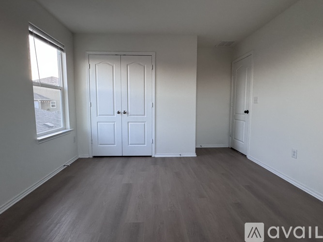 A room with a white door and a window with a view of a building outside.