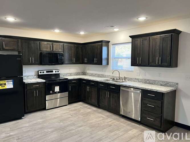 A kitchen with black cabinets and appliances is available for rent.