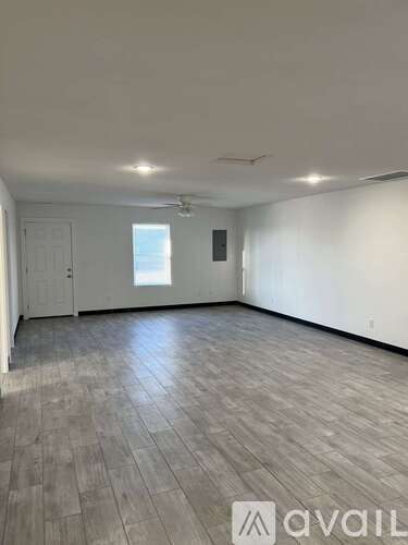 A spacious room with wooden flooring and white walls.