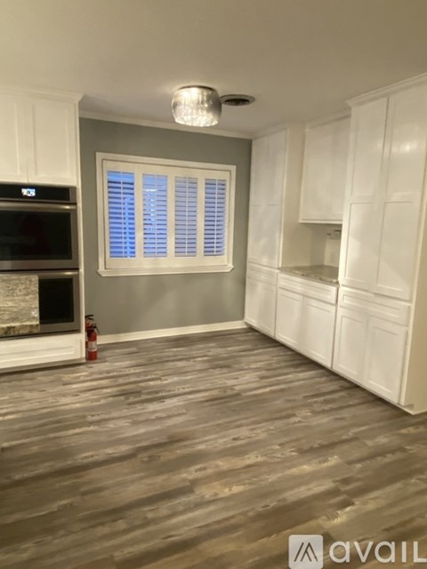 A kitchen with white cabinets and a grey wall.