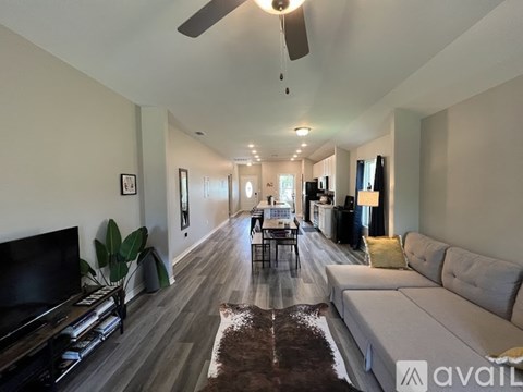 A living room with a grey couch and a brown rug.