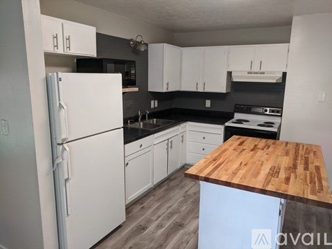 A kitchen with a white refrigerator and wooden countertop.