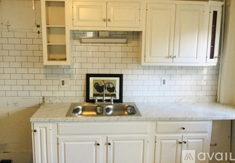 A kitchen with white cabinets and a marble countertop.