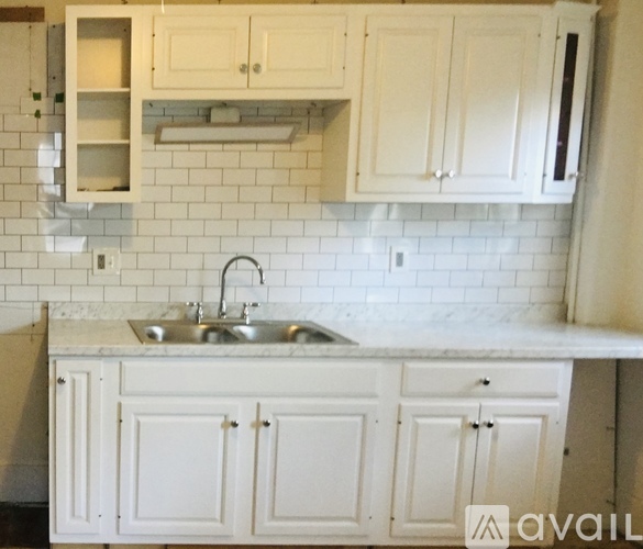 A kitchen with white cabinets and a marble countertop.