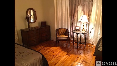 A bedroom with a bed, chair, and lamp.