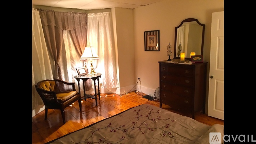 A room with a chair, a table, a dresser, and a mirror.