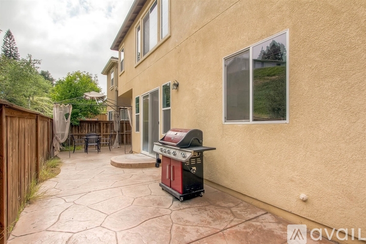 A backyard with a BBQ grill and patio furniture.
