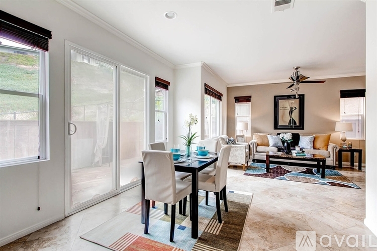 A dining room with a table set for four and a couch in the background.