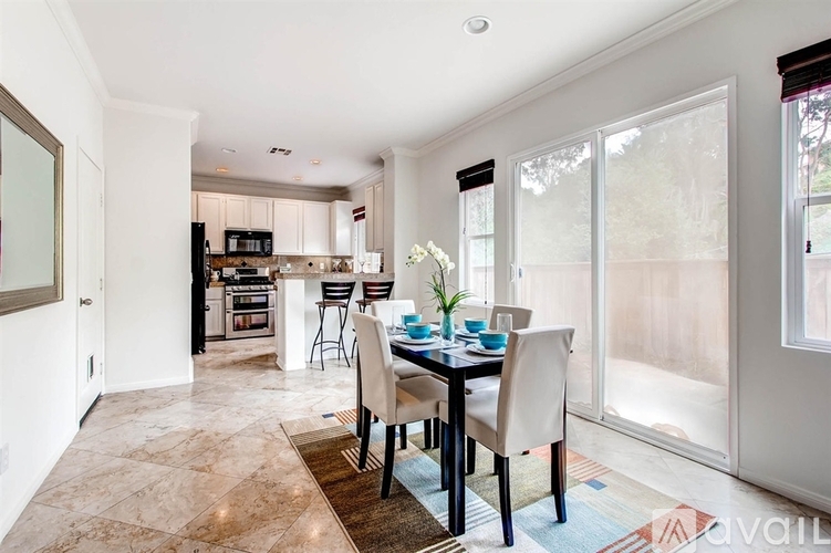 A dining room with a table set for two and a kitchen in the background.