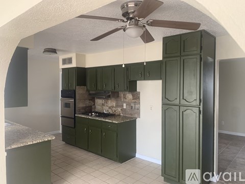 A kitchen with green cabinets and a marble countertop.