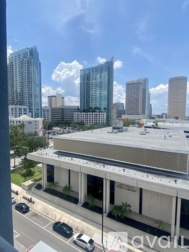 A view of a cityscape with a building in the foreground and several high-rise buildings in the background.