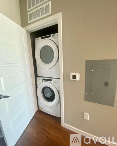 A white washer and dryer are stacked in a small laundry room.