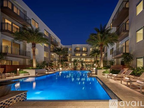 A swimming pool in front of a building with palm trees.