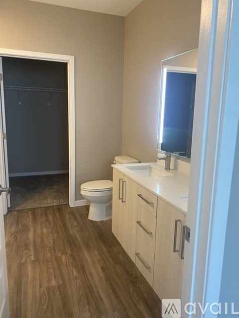 A bathroom with a toilet, sink, and wooden floors.