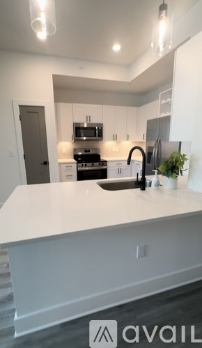 A modern kitchen with a white countertop and stainless steel appliances.