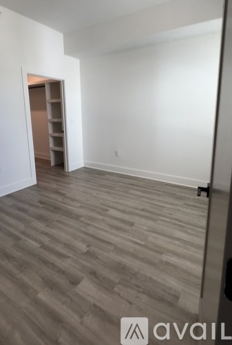 A room with wooden flooring and a closet with shelves.