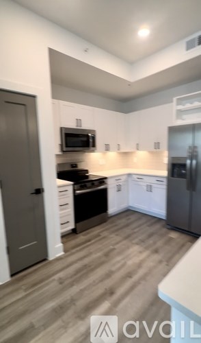 A kitchen with a refrigerator, microwave, and oven.