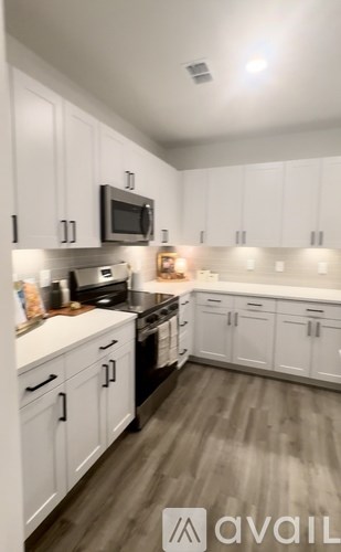 A kitchen with white cabinets and a black microwave.