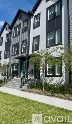 A modern two-story building with a black and white exterior and a green lawn in front.
