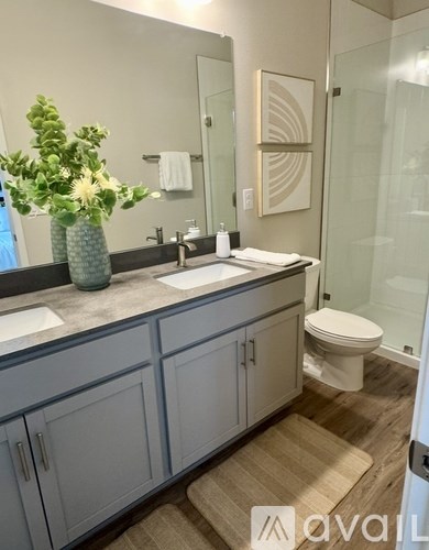 A bathroom with a sink, toilet, and a vase of flowers.